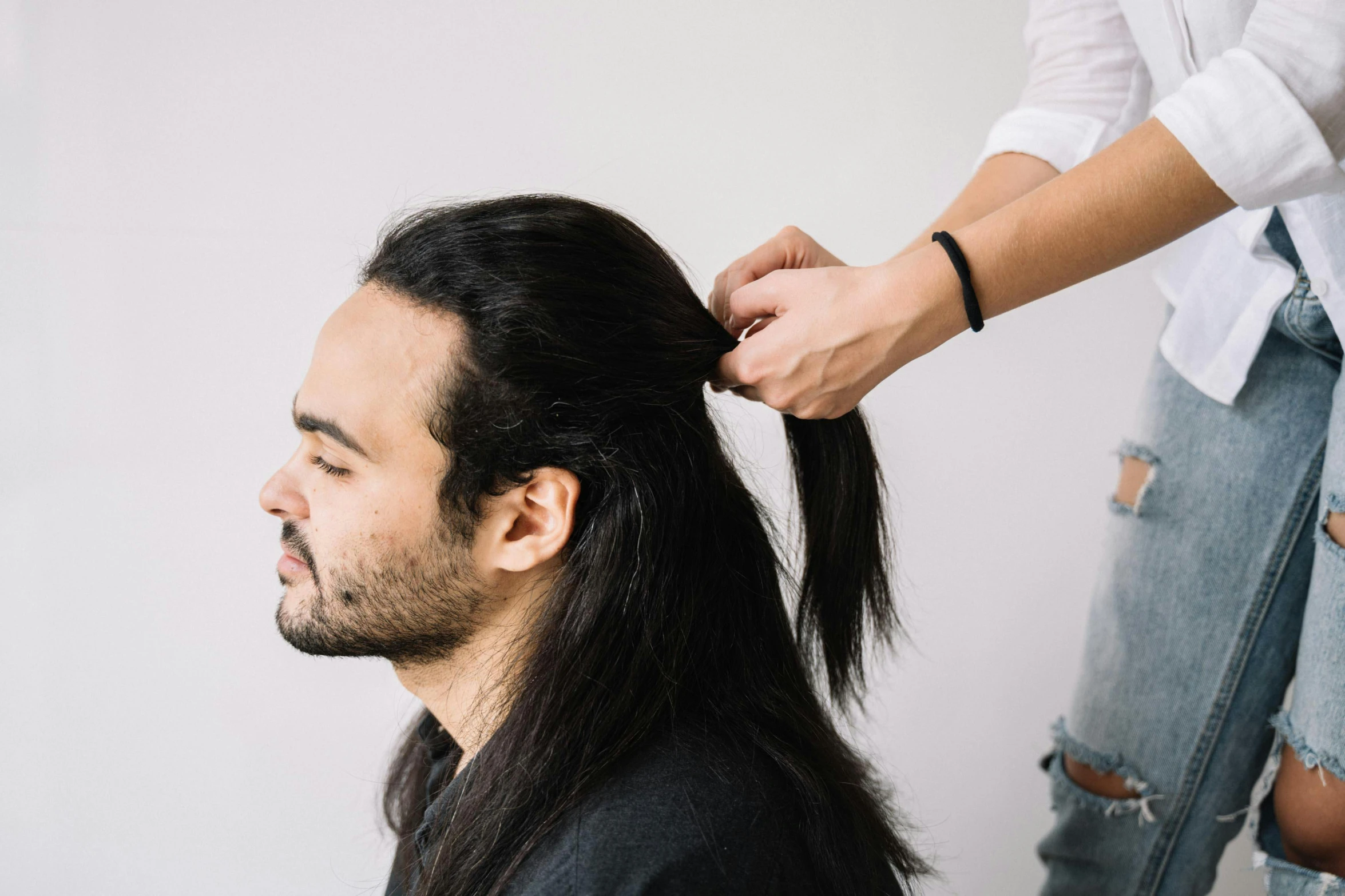 a man with long hair is getting a haircut