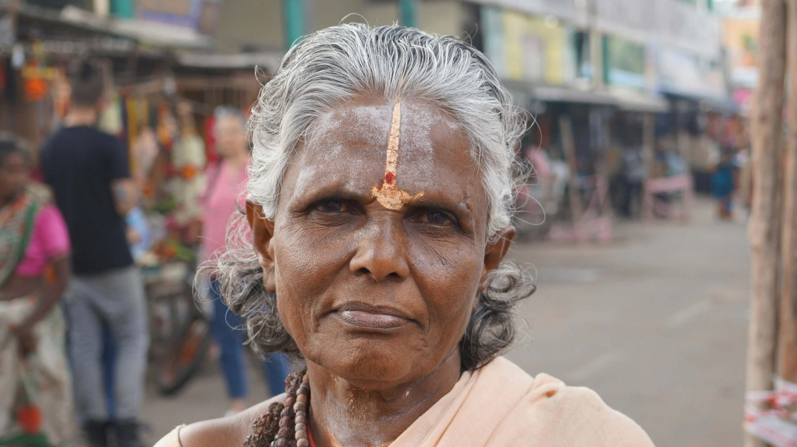 a older woman stands on the street wearing a headdress