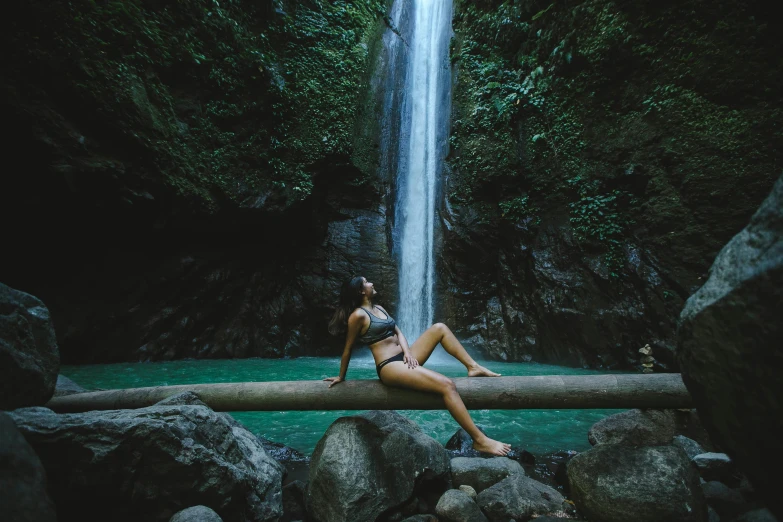 the woman is sitting by the waterfall and posing for the po