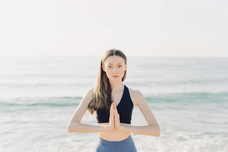 a girl standing with her hands in the air at the beach