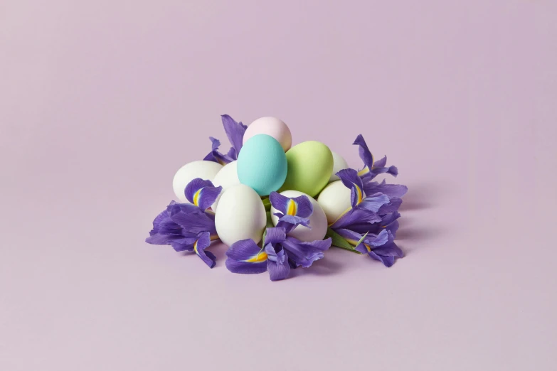 several decorated eggs sitting in front of flowers on a purple surface