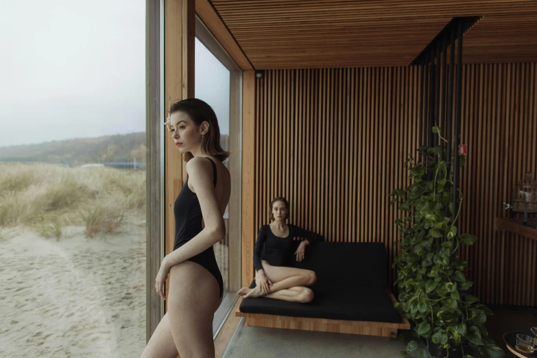 two women in black outfits sitting in the sand