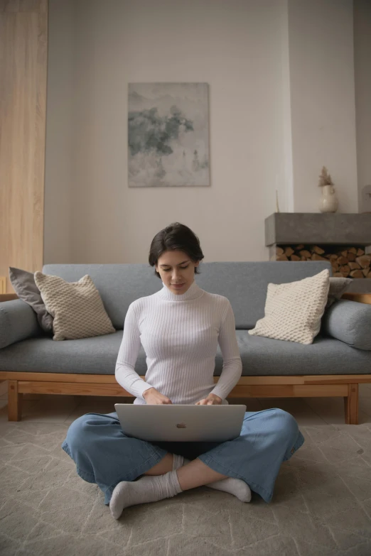 the woman sitting on the floor uses a laptop