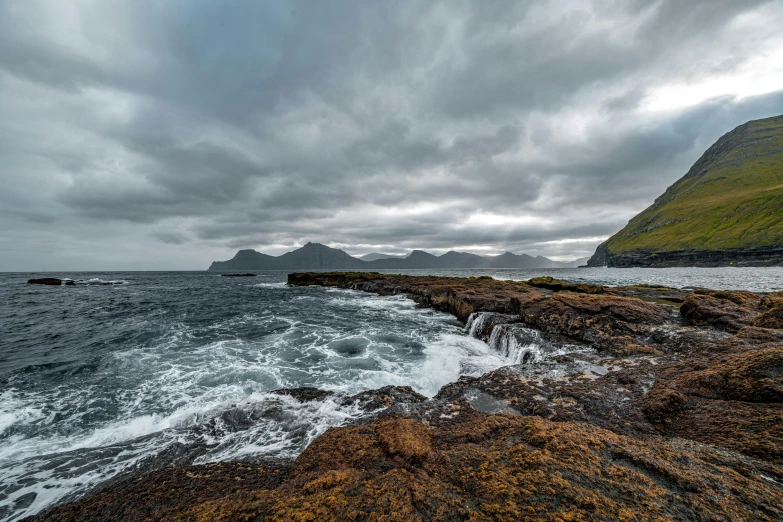 a rocky coast with a small wave in the ocean