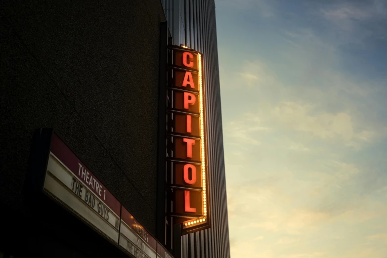 a tall building with a neon sign and a blue sky in the background