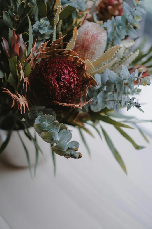 a vase filled with flowers and leaves sitting on a table