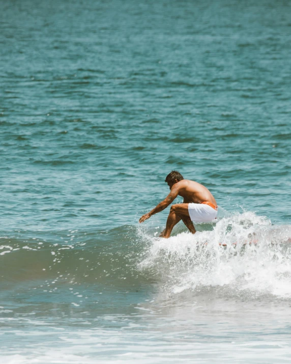 surfer crouching down to balance while surfing on the ocean waves