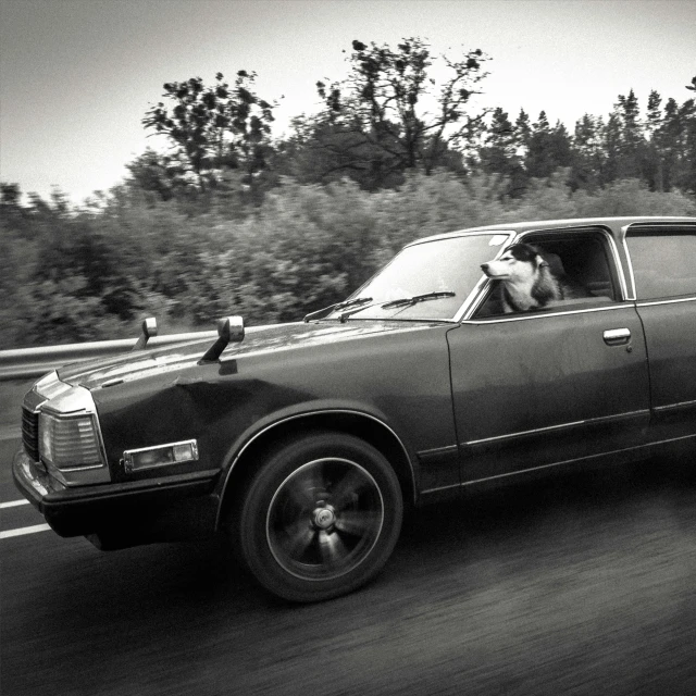 a black and white po of a classic car traveling along the road