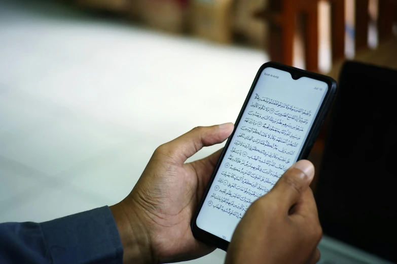 someone holding up their computer while reading a book