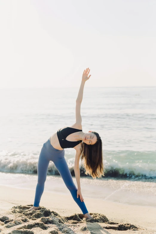 a woman doing yoga on a beach near the ocean
