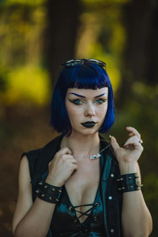 a woman with blue hair is dressed in goth garb