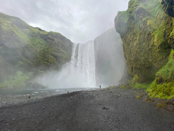 a waterfall in a hilly area, with a person looking at it