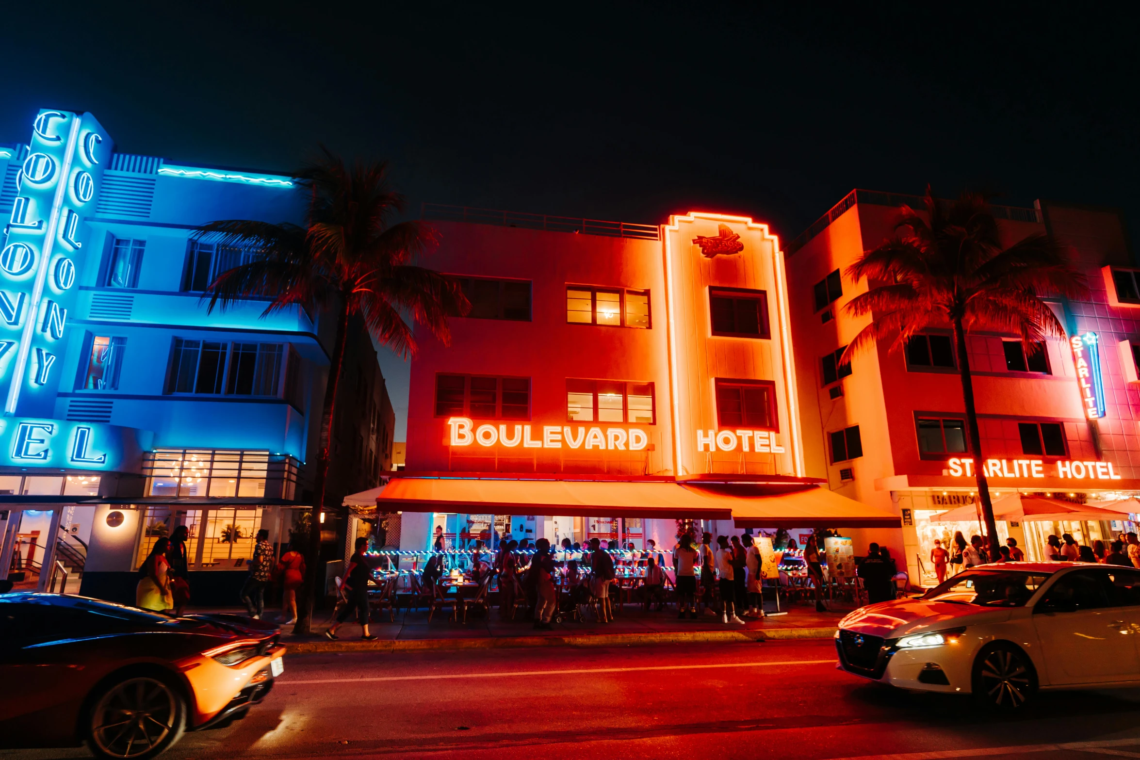 cars drive by an illuminated el at night