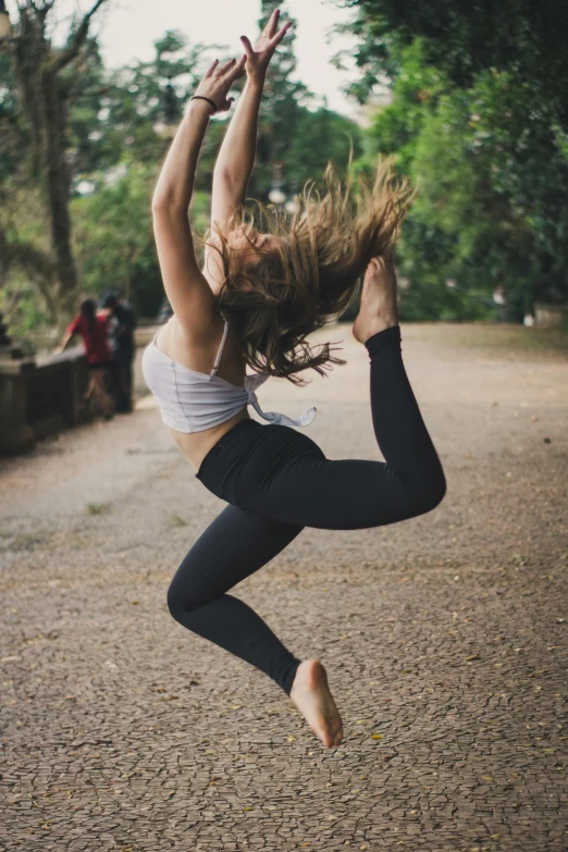 the young woman is doing yoga on a dirt surface