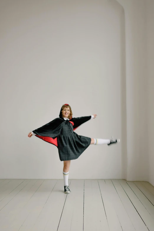 a  dressed in black and red poses on the floor