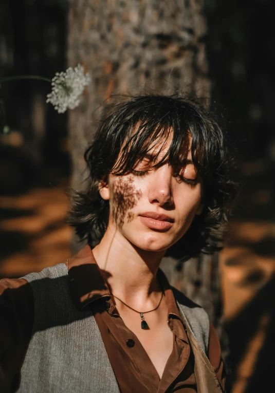 a person standing near a tree with sun shining on her face