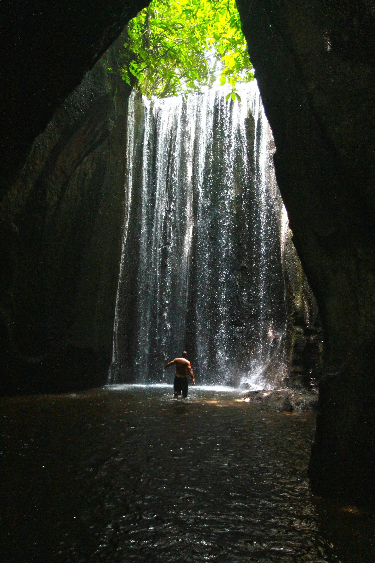 a large waterfall that is near a person holding an umbrella