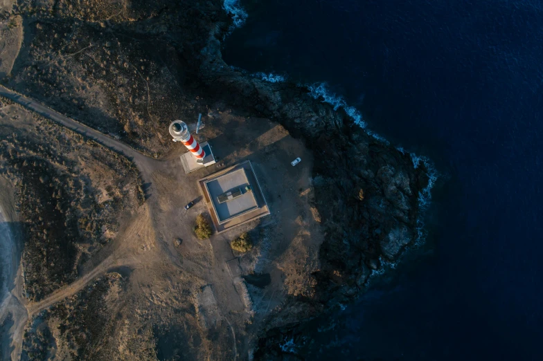 an aerial view of a lighthouse at the edge of the water