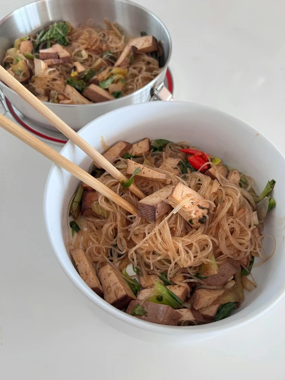 two metal bowls with food inside on a table