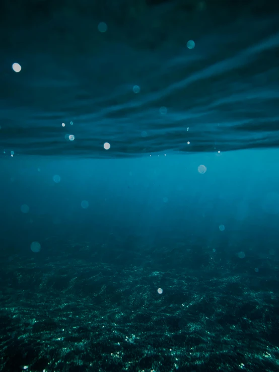 an underwater view shows bright lights and blue water