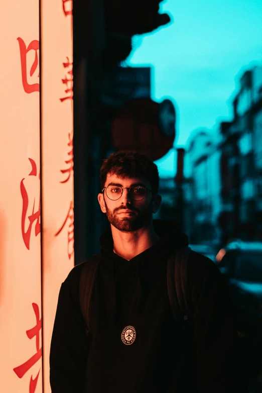 a man in a black hoodie standing in front of chinese writing