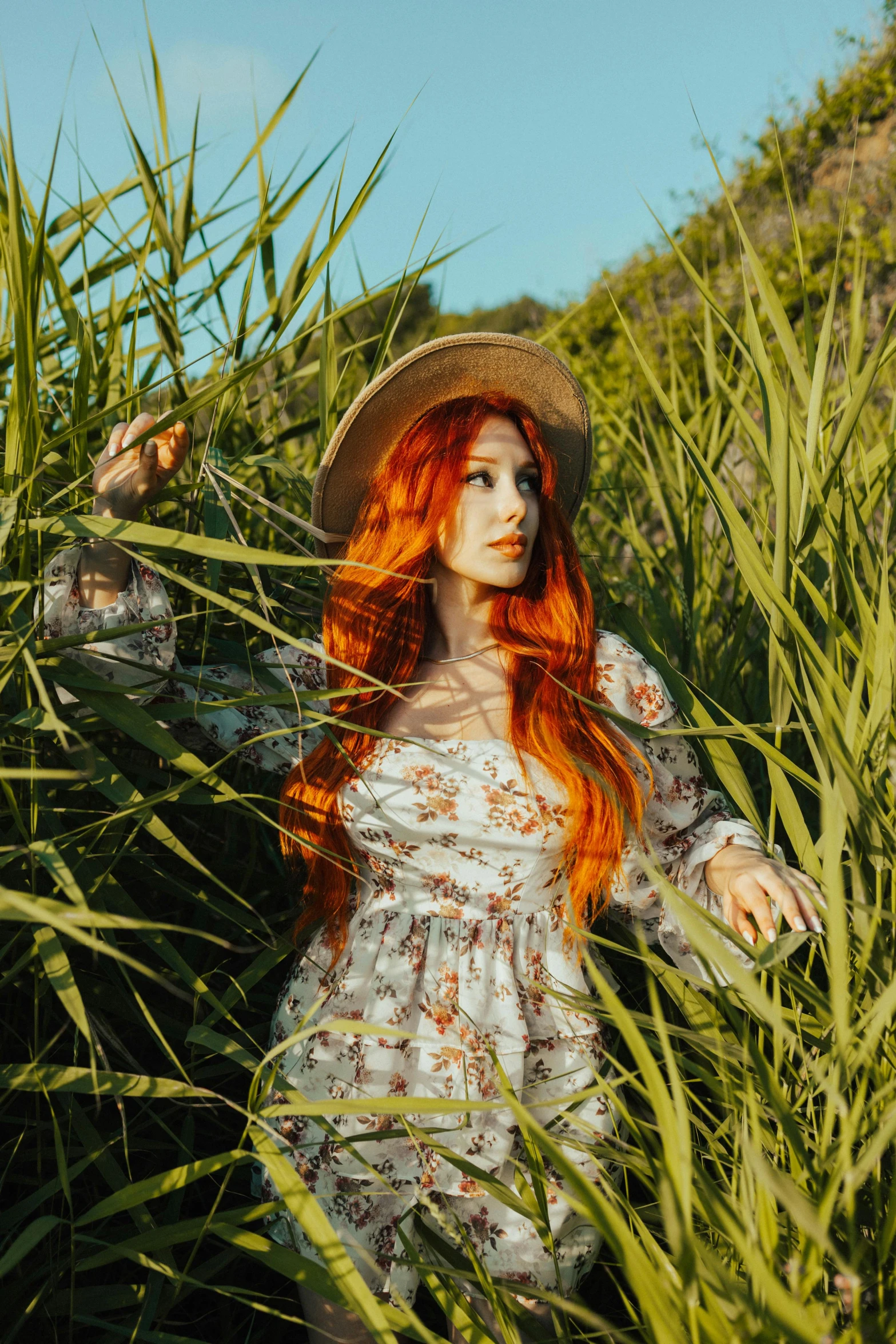 a young woman poses while sitting in a field