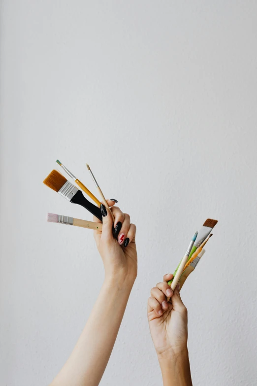 a person holding four different brushes in one hand