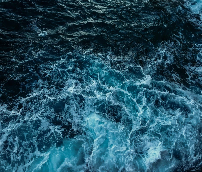 a view from above of water with white and blue bubbles