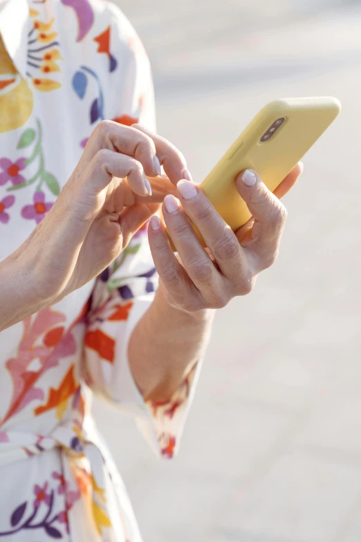 woman in floral dress texting on phone outdoors