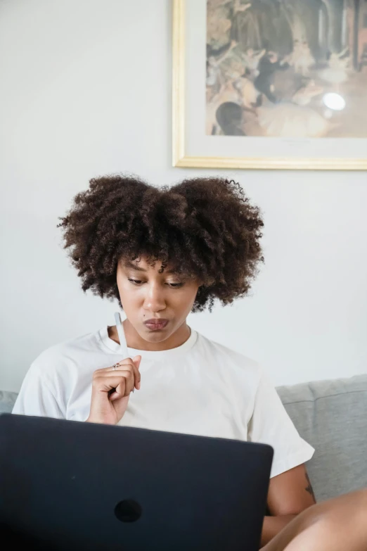 a woman sits with a laptop on her lap top