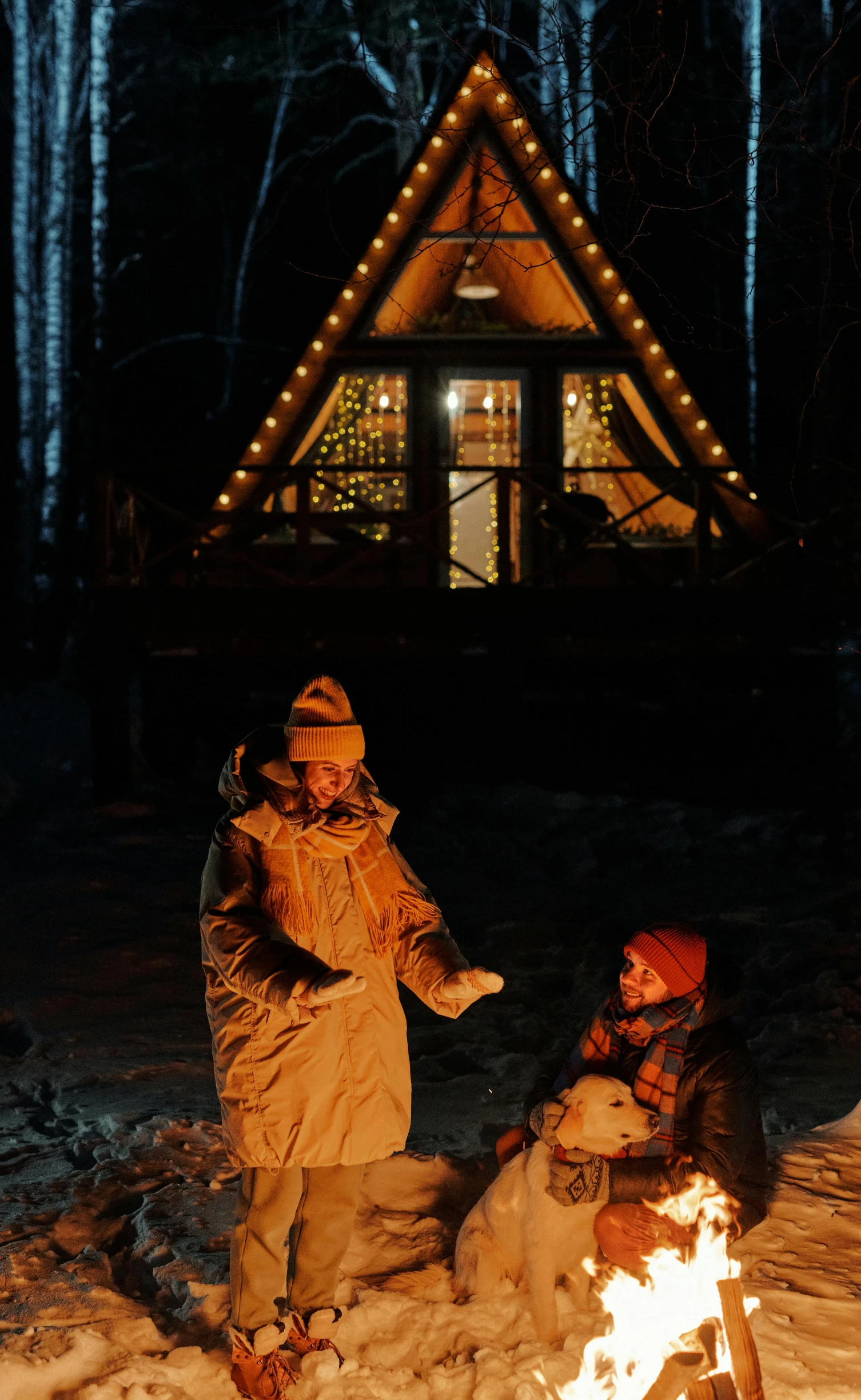 two people by a small cabin covered in snow