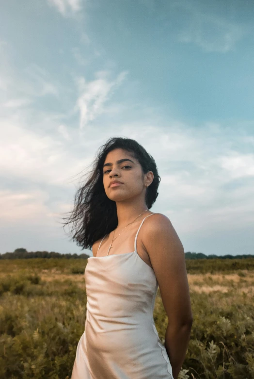 an asian woman stands in a field at dusk