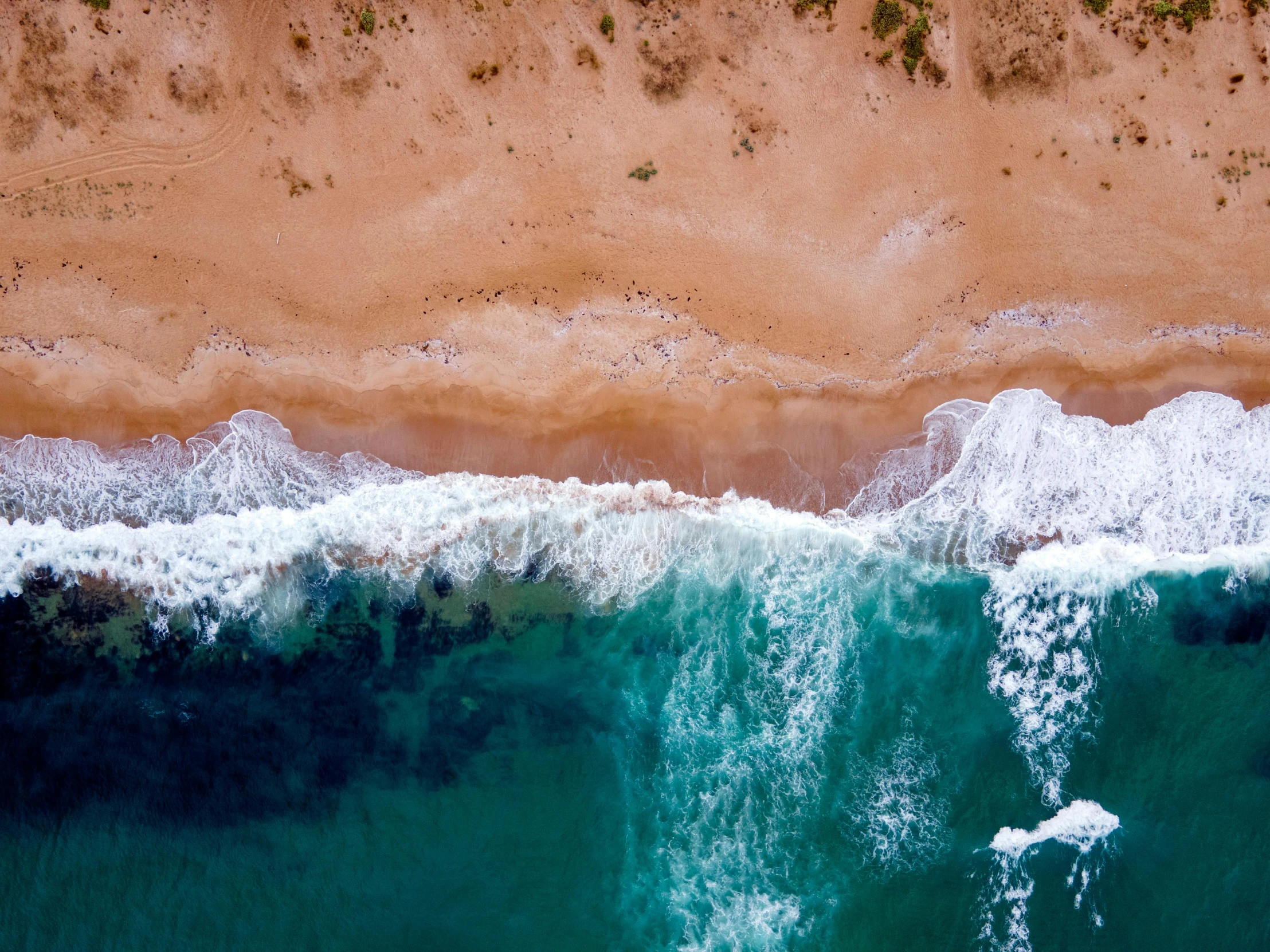 an aerial view of ocean waves hitting the beach