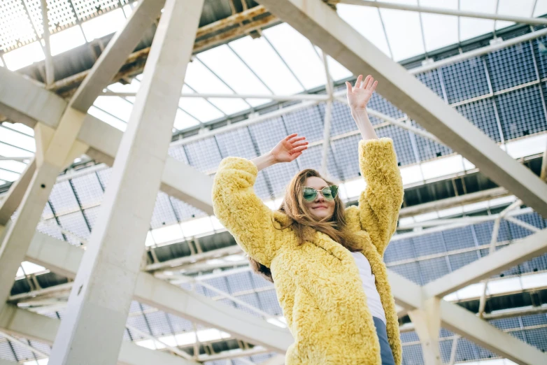 woman in yellow sweater holding her hand up in the air