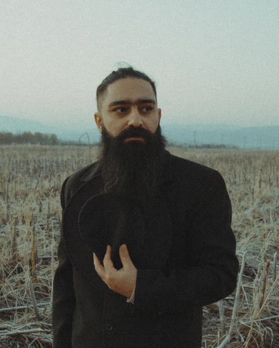 a man with a long beard standing in a field