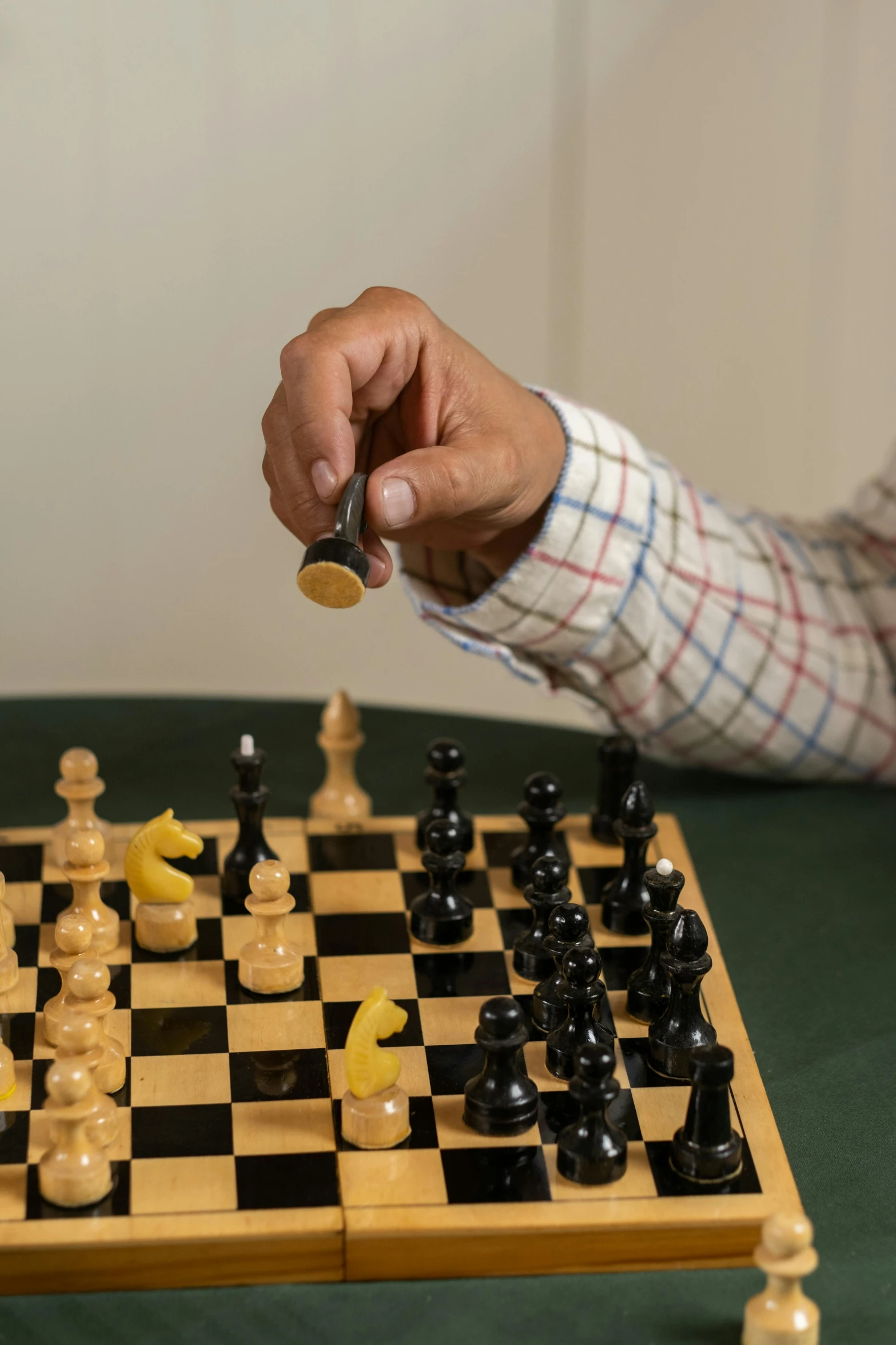 man holding his watch while playing chess with a giant set
