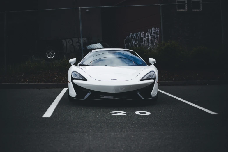 a white car sitting in a parking lot with graffiti on the wall