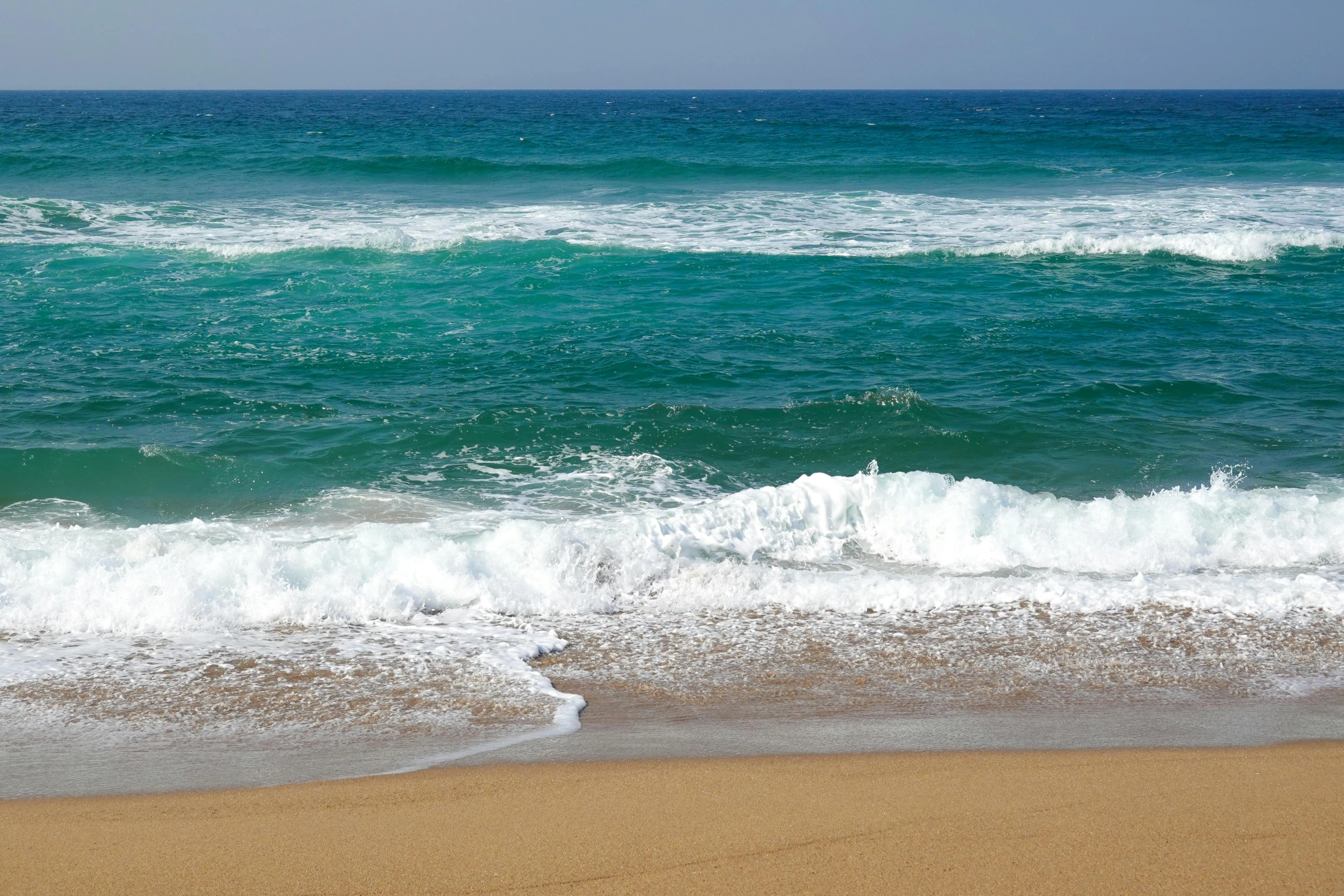 the waves on the shore of a sandy beach