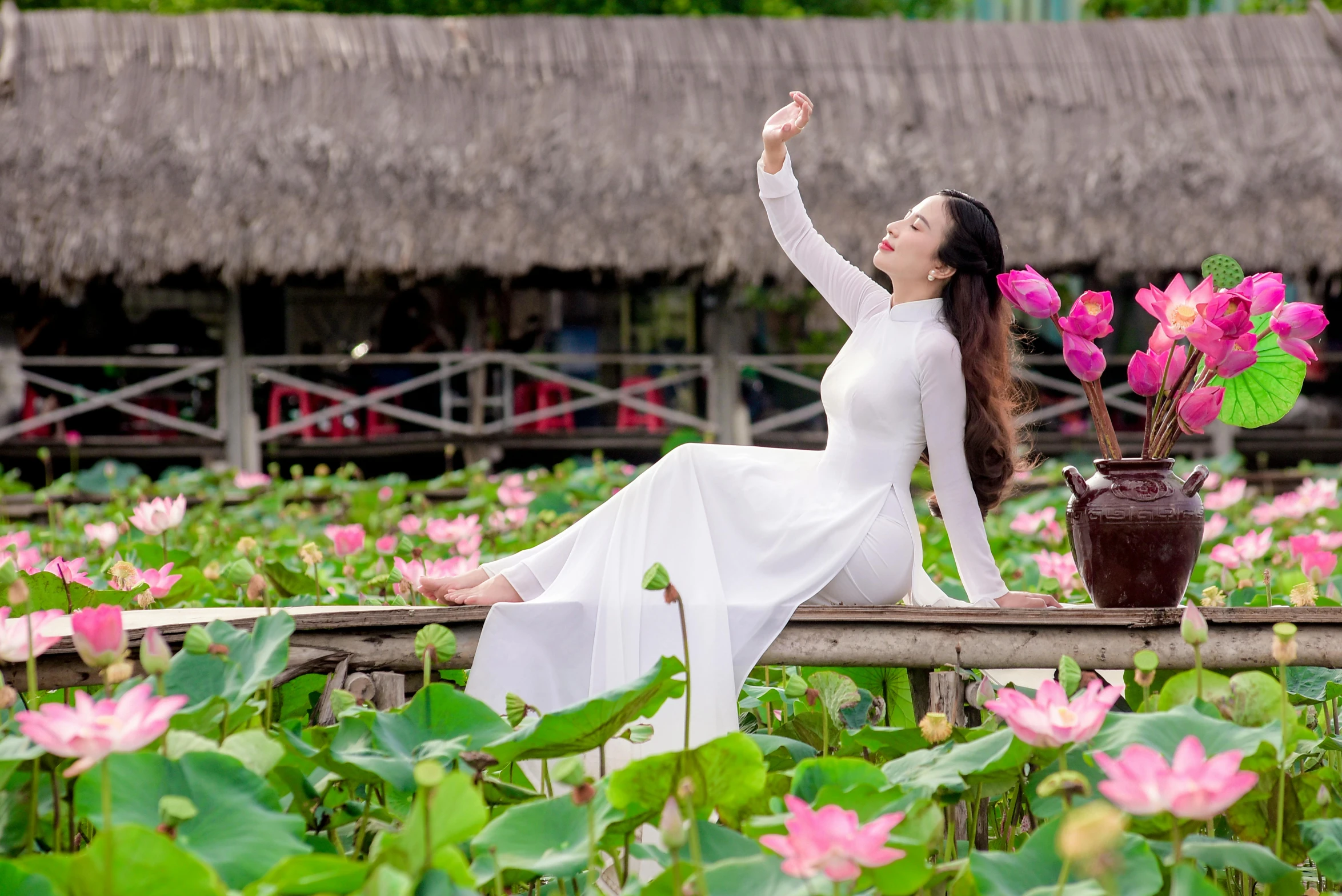 a woman sitting on a fence next to pink flowers