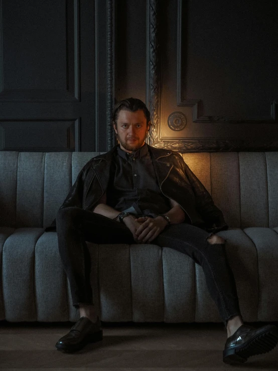 man sitting on couch in dark room with two lights on