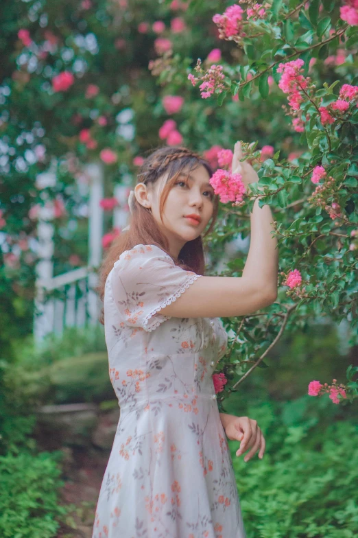 girl standing near bush with flower bush in bloom