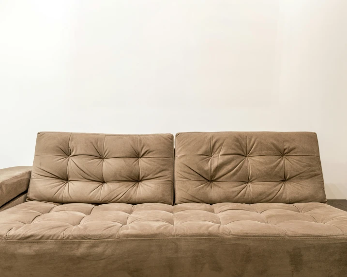 a tan sofa against a white wall with no one sitting on it