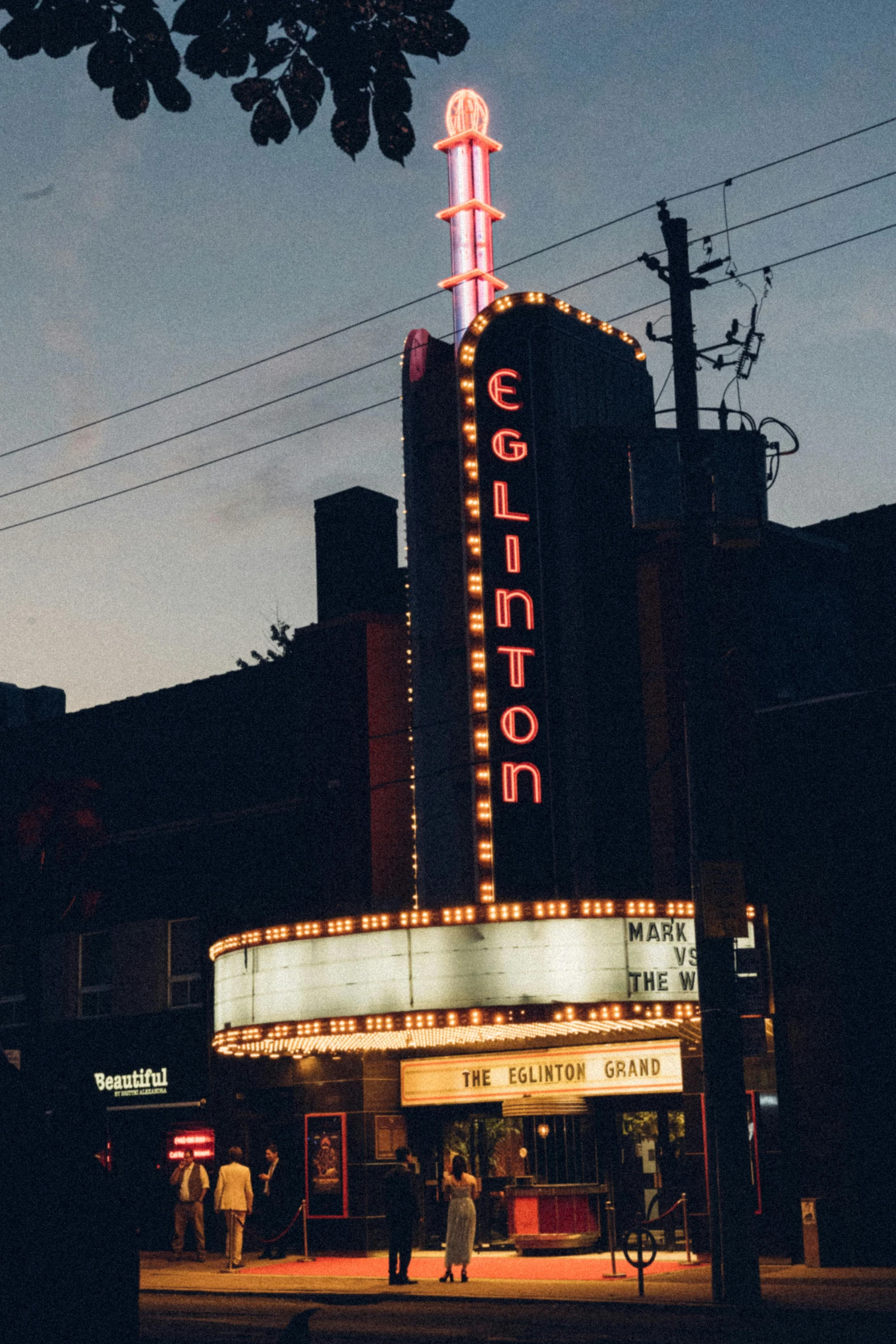 a night scene of a theater with people walking around the building