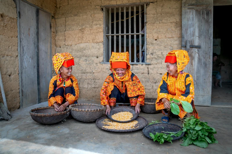three young women with colorful costumes are preparing food