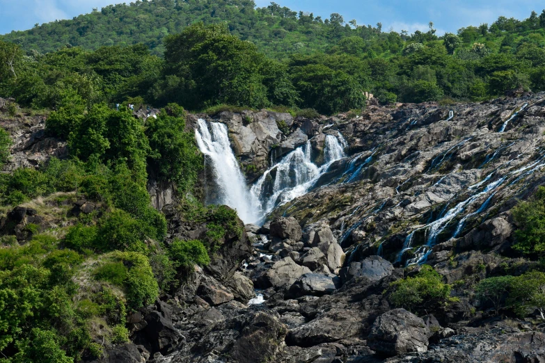 a waterfall in the middle of rocks with forest