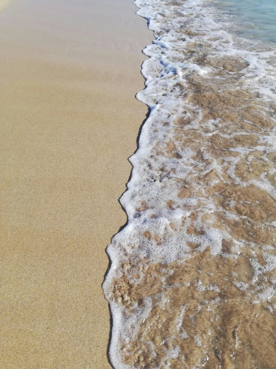 a beach with white and blue waves rolling up on it