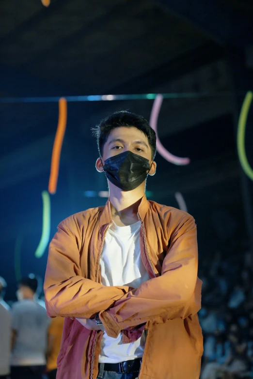 an asian male in black mask with arms crossed