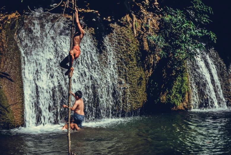 a man hanging from a rope above water