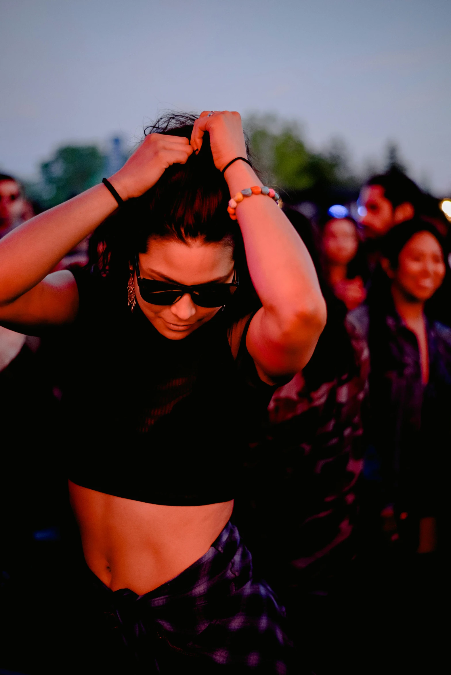 a woman standing in front of a crowd wearing sunglasses