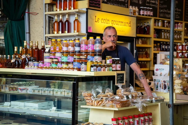 a man in a store pointing at shelves filled with various kinds of goods